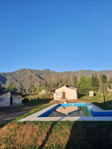 a swimming pool with a house and mountains in the background at Starry Lodge in Ciudad Lujan de Cuyo