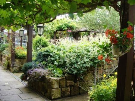 a garden with flowers and plants on a wall at Ellerby Country Inn in Ellerby