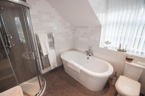 a bathroom with a tub and a shower and a toilet at Ellerby Country Inn in Ellerby