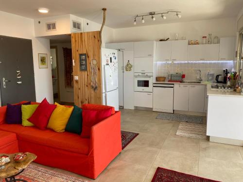 a red couch with colorful pillows in a kitchen at Acre sea view 11th floor apartment in ‘Akko