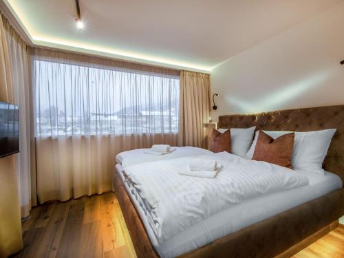 um quarto com uma cama grande e uma janela grande em Apartments B-HOME, Bramberg am Wildkogel em Bramberg am Wildkogel