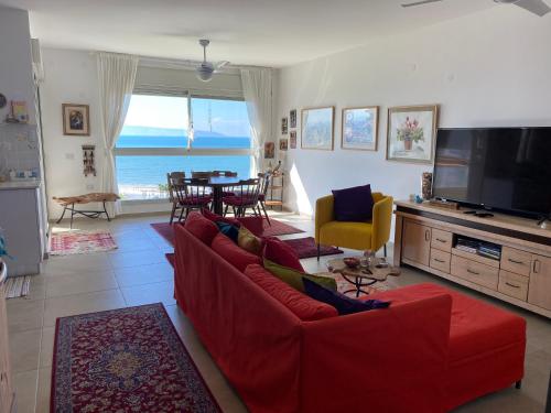 a living room with a red couch and a television at Acre sea view 11th floor apartment in ‘Akko