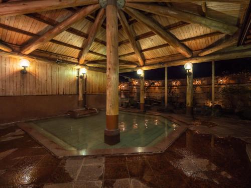 a swimming pool in a building with a wooden ceiling at Matsunoi in Minakami