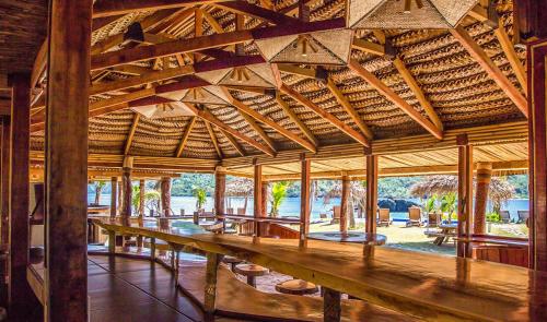 un gran pabellón de madera con mesas y bancos de madera en Barefoot Kuata Island Resort en Kuata