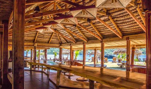 a large wooden pavilion with wooden tables and benches at Barefoot Kuata Island Resort in Kuata