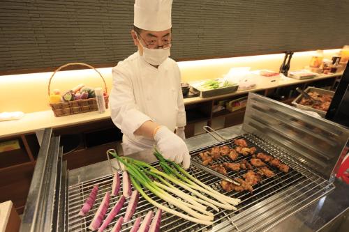 a chef preparing food on a grill in a kitchen at Matsunoi in Minakami