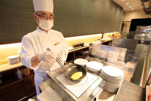 a chef in a kitchen preparing food in a wok at Matsunoi in Minakami