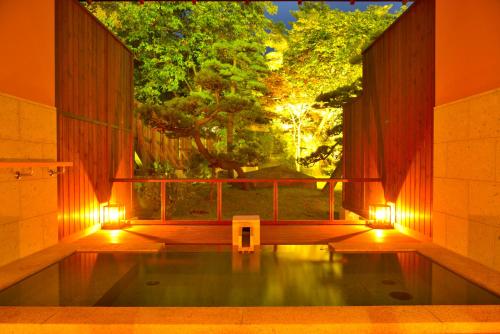a bath tub with a window with a view of a tree at Matsunoi in Minakami