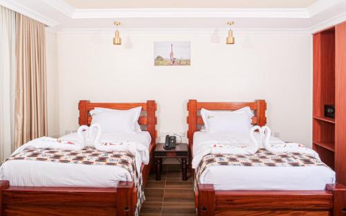 um quarto de hotel com duas camas e uma mesa em Pori City Hotel em Nairobi