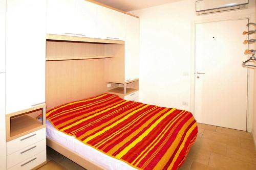een slaapkamer met een bed met een kleurrijk gestreepte deken bij Residence Villaggio A Mare, Lido Altanea in Caorle