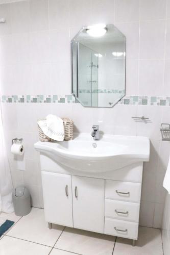 a white bathroom with a sink and a mirror at Green Scape Flatlet in Pretoria