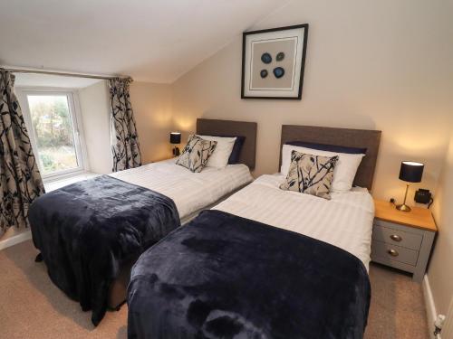 a bedroom with two beds and a window at The Cottage in Tetbury