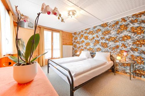 ein Schlafzimmer mit einem Bett und einer Pflanze auf einem Tisch in der Unterkunft Pension Aaron am See in Grächen
