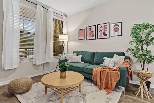 a living room with a green couch and a table at New! King Bed Trendy 1 BR Resort Style w/ Pool in Houston