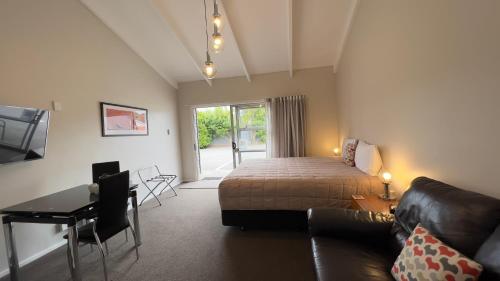 ein Schlafzimmer mit einem Bett, einem Sofa und einem Schreibtisch in der Unterkunft Cedar Lodge Motel in Timaru