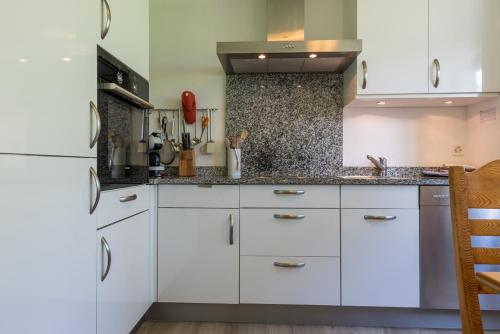 a kitchen with white cabinets and a white refrigerator at Jewel Duplex in Fieschertal