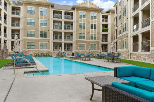 a pool with chairs and tables in a building at New! King Bed Trendy 1 BR Resort Style w/ Pool in Houston