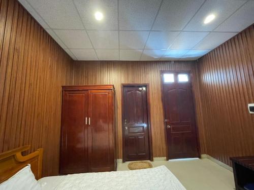 a bedroom with wood paneled walls and two doors at Đắk G'lung Bungalow in Bu Yal (1)