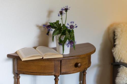 a table with an open book and a vase of flowers at Jewel Duplex in Fieschertal