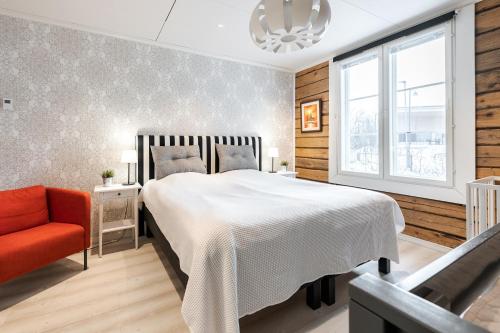 una camera con un letto bianco e una sedia rossa di Villa Härmälä a Tampere