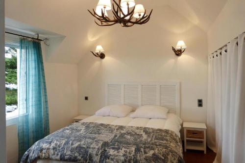 um quarto com uma cama e um lustre em Holiday Home Plougasnou - BRE05101j-F em Plougasnou