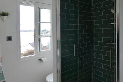 uma casa de banho com um chuveiro com azulejos verdes e uma janela. em Holiday Home Plougasnou - BRE05101j-F em Plougasnou