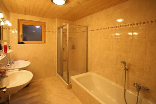 a bathroom with a shower and a tub and a sink at Chalet, Königsleiten in Königsleiten