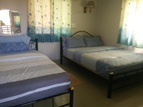 twee bedden in een kamer met blauwe gordijnen bij ต้งโฮมหละปูน ณ ตูบแก้ว in Lamphun