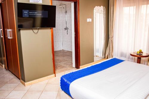 a bedroom with a bed with a flat screen tv at Lishi Resort Hotel in Kampala