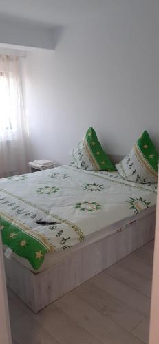 un letto con lenzuola e cuscini verdi e bianchi di Home Sweet a Iaşi