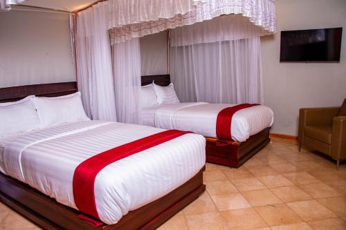 a hotel room with two beds and a chair at Lishi Resort Hotel in Kampala