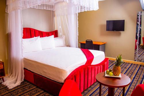 a hotel room with a red bed and a table at Lishi Resort Hotel in Kampala