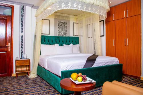 a bedroom with a green canopy bed with fruit on a table at Lishi Resort Hotel in Kampala