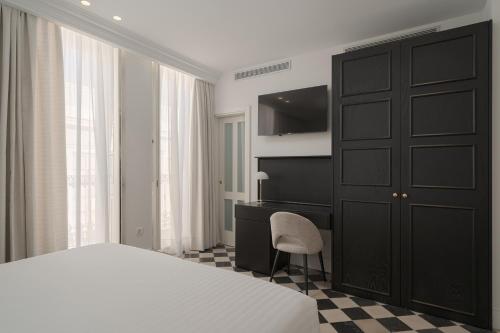 1 dormitorio con armario negro, cama y escritorio en Boutique Hotel Cordial La Niña de Vegueta, en Las Palmas de Gran Canaria
