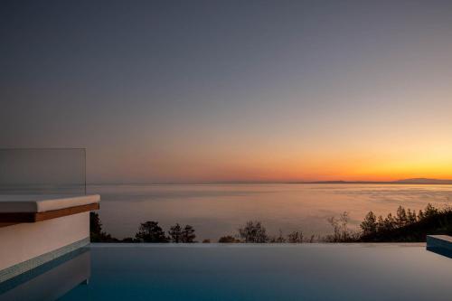 a pool with a view of the ocean at sunset at Zante Fiore Suites in Xirokástellon