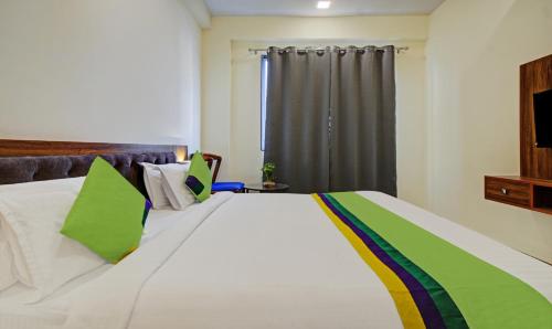 a bedroom with a large white bed with green pillows at Tripli Hotels Le Shelton in Udaipur
