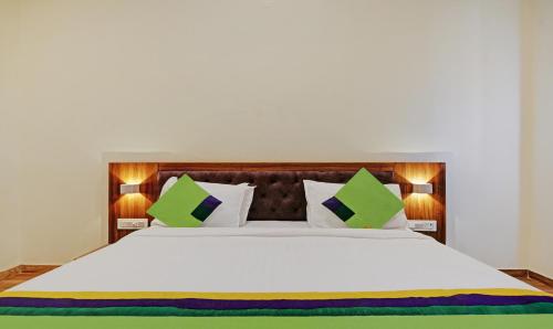 a bedroom with a large white bed with green pillows at Tripli Hotels Le Shelton in Udaipur