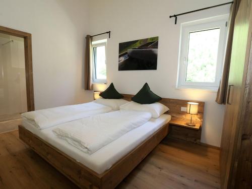 a large bed in a room with two windows at Apartment in Milders with Stubai SuperCard in Neustift im Stubaital