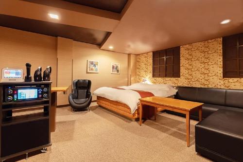 a bedroom with a bed and a tv and a couch at ホテル ドルフィンリゾート 犬山 -大人専用- in Kakamigahara