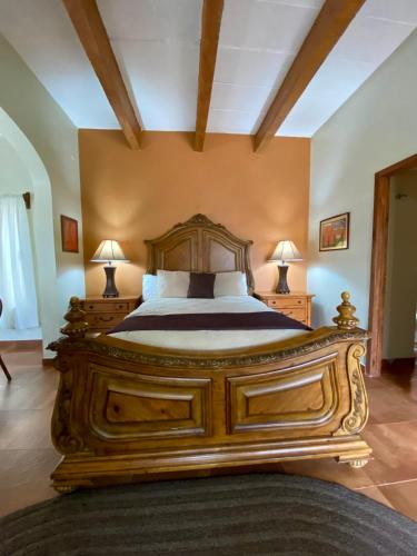 a large wooden bed in a room with two lamps at Hotel Casa María Félix in Álamos
