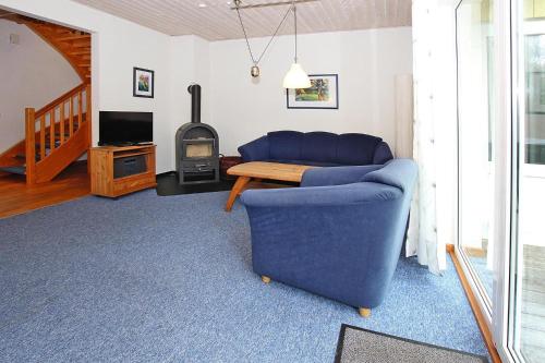 a living room with a blue couch and a wood stove at Ferienanlage im Müritz-Nationalpark, Mirow in Mirow