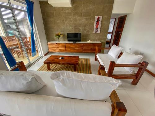 a living room with a couch and chairs and a tv at Aqua Resort in Diani Beach