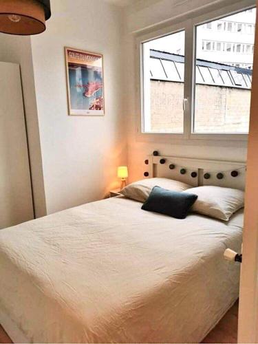 Schlafzimmer mit einem großen weißen Bett und einem Fenster in der Unterkunft Bel appartement rénové, centre de Vannes in Vannes