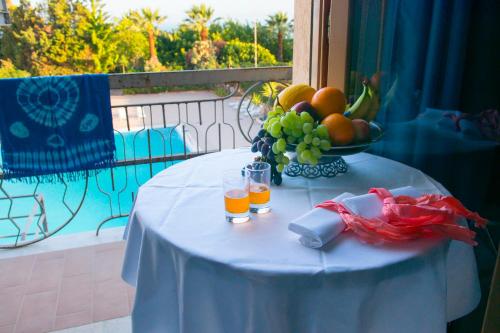 a table with a bowl of fruit and glasses of orange juice at Hotel Dei Pini in Porto Empedocle