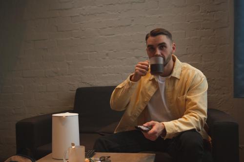 a man sitting in a chair drinking a cup of coffee at Campus Community A-Rooms in Kyiv