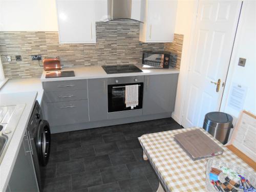 a small kitchen with a stove and a dishwasher at The View Deer Park Luxury Apartment in Edinburgh