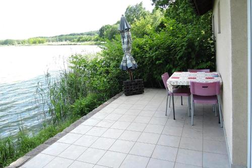un patio con mesa, sillas y sombrilla en Holiday House in Szczecin at the lake with parking space for 4 persons, en Szczecin