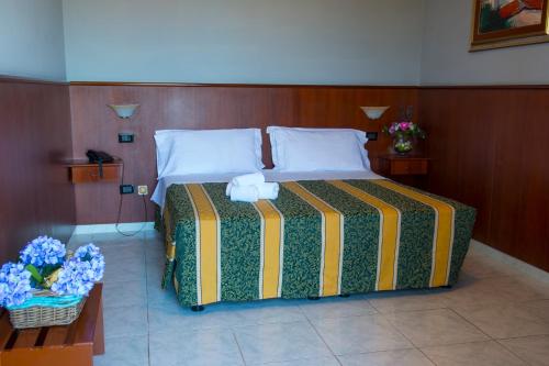a bedroom with a bed with a striped blanket and flowers at Hotel Dei Pini in Porto Empedocle