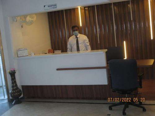 a man standing behind a counter with a mask on at Hotel Kewal in Nashik