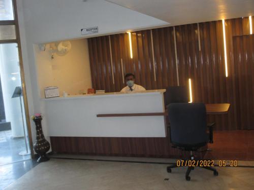 a man sitting at a counter in a hotel lobby at Hotel Kewal in Nashik